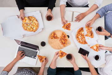 The office staff eat pizza and drink coffee in the business office. They have a break in their...