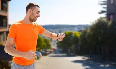 sport, technology and healthy lifestyle concept - smiling young man with smart watch or fitness tracker over san francisco city background