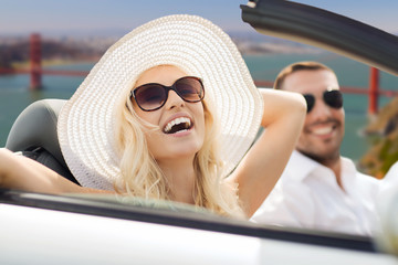 road trip, travel and people concept - happy couple driving in convertible car over golden gate...