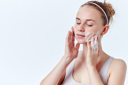 Teenager Skincare. Beautiful Teenage Girl With Freckles And Blue Eyes Using Foaming Cleanser. Face Washing Concept Isolated On White Background.