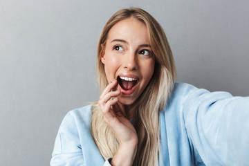 Close up of excited young blonde girl taking a selfie