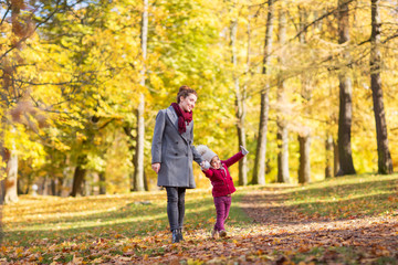 Fototapeta premium family, season and people concept - happy mother and little daughter walking along autumn park