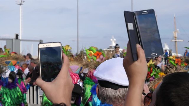 Spectators in crowd take mobile phone video of public carnival festival procession show in Tenerife