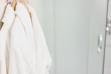 Clean white towel and bathrobe on a hanger prepared to use. Bathroom Inside rooms of a apartment or hotel.