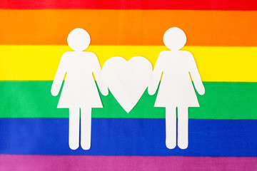gay pride, homosexual and lgbt concept - female couple white paper pictogram on rainbow flag...