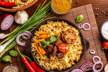 Homemade Uzbek pilaf from lamb served in cast iron cookware.