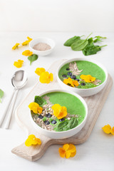 green spinach smoothie bowl with blueberry, chia seed and edible pansy flowers