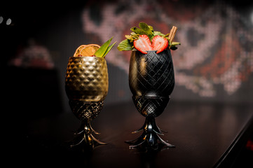 Two cocktails in the pineapple form cups on the dark background