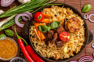 Homemade Uzbek pilaf from lamb served in cast iron cookware.