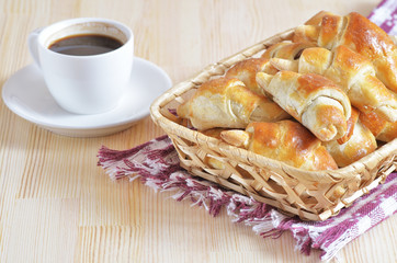 Homemade croissants in a wicker basket on a tablecloth