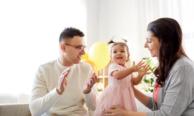 family, holidays and people concept - mother, father and happy little daughter clapping hands at...