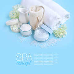 Obraz na płótnie Canvas Spa composition with cream, salt, towel and flowers on a blue background.