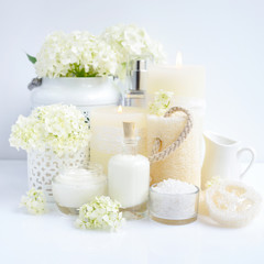 Spa composition with candles, cream, salt and flowers of hydrangea on a white background
