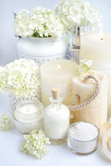 Fototapeta na wymiar Spa composition with candles, cream, salt and flowers of hydrangea on a white background