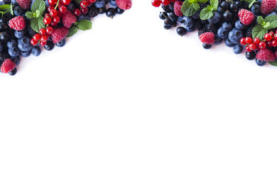 Mix berries and fruits at border of image with copy space for text. Ripe blueberries, blackberries, raspberries and currants on white background. Top view.
