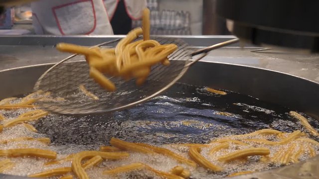 Cooking sweet snacks boiling in oil at street food point during festival carnival in Tenerife