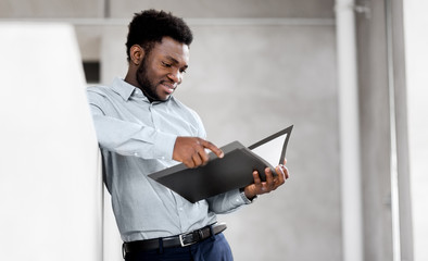 business, people and corporate concept - smiling african american businessman with folder at office