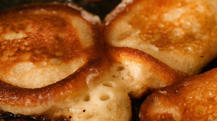 Closeup view freshly toasted pancakes frying in bubble vegetable oil on preheat cast iron pan at home