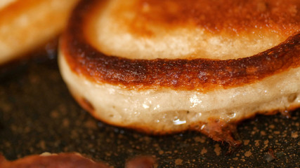 Closeup view freshly toasted pancakes frying in bubble vegetable oil on preheat cast iron pan at home