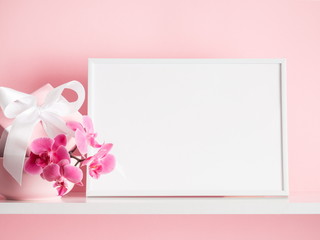 Photo frame mock up, beautiful flowers bouquet on the shelf, gift with white satin bow, pink orchid...