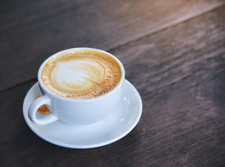 Coffee with heart-shaped cream, white cup on the wood table.