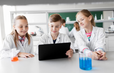 Fototapeta premium education, science and technology concept - kids with tablet pc computer studying chemistry at school laboratory