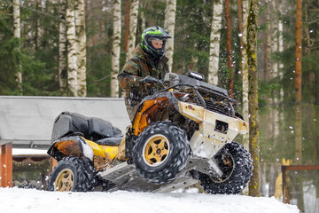 Fototapeta na wymiar Extreme ATV rider gets on snow hill