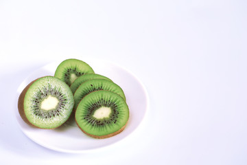 A kiwi fruit is sliced on a white background