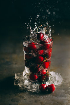 Close up of splashing red cherry in glass with ice
