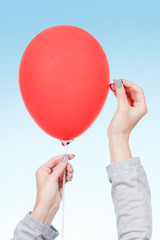 Danger concept. Hand holding needle near balloon isolated on white.