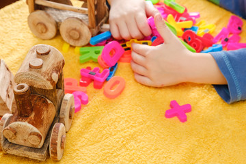Obraz na płótnie Canvas Little baby hand playing with colorful toys and letters