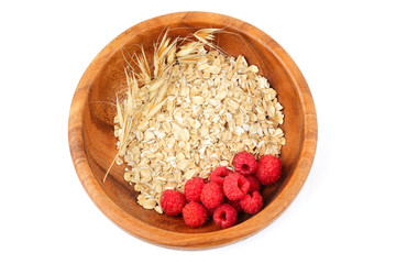 Oatmeal with raspberries in a wooden plate.