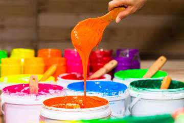 scoop orange color of plastisol ink out the barrel in store. several colors of plastisol ink in tee shirt factory main color is blue green yellow orange red and black color