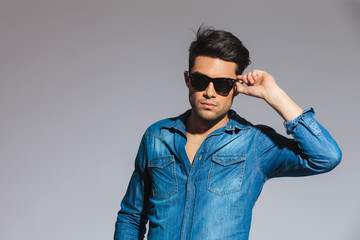 Fototapeta premium handsome young man wearing a denim shirt holds his sunglasses