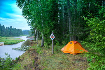 Orange tent on the river bank.  Forest tourism.
