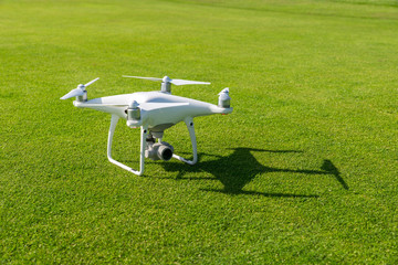 White drone camera in front of green grass from above