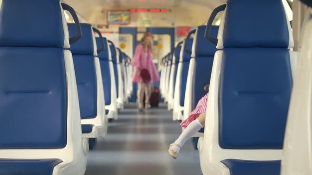 Cheerful little girl with her mom walks into the empty train car