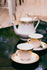 Set of vintage classic style tea cup and jug on table with old style decoration in background.
