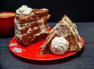 sour cream cake with cream and fresh coffee in a red mug on a dark wooden background