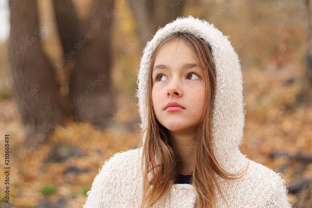 Wall mural close-up portrait of beautiful thoughtful dreaming little girl in white hoody coat staying in autumn