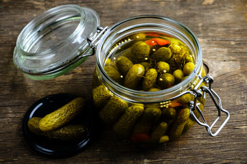 Glass jar with fresh low-salt pickled homemade cucumbers on wood