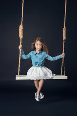 little girl on a swing in a denim jacket
