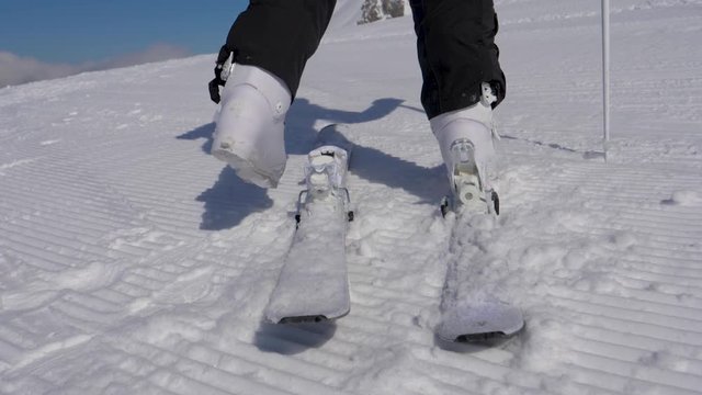 Close Up Skier Stepping Into Ski Bindings With His Ski Boots On A Sunny Day