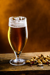 Beer glass with dark cold beer with bubble froth and peanuts on 