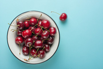 Obraz na płótnie Canvas Sweet cherries in a bowl, on a blue background