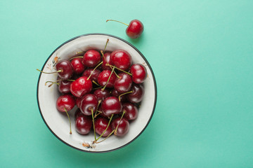 Sweet cherries in a bowl, on a green background