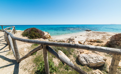 Fototapeta na wymiar Wooden fence by the shore in Santa Giusta beach in Castiadas