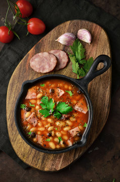 Baked beans with sausages on cutting board