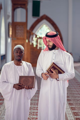 Two religious muslim man walking together inside the mosque