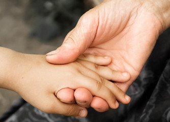 Hands of a little girl and an old grandmother. Hands of a little kids holding elderly man, World...